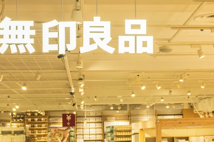 People shopping inside a large, brightly lit Muji store with various household products displayed