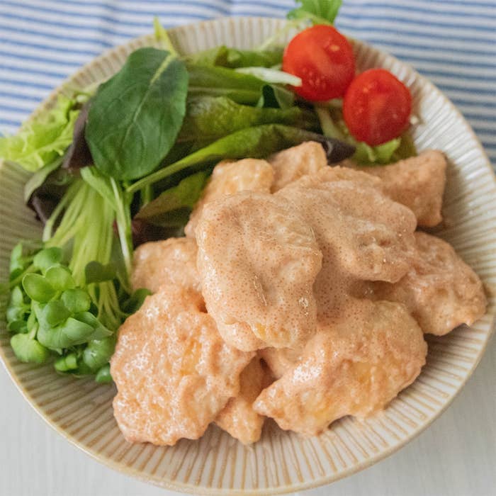 明太子のソースがかかった鶏ささみとサラダが盛りつけられた白い皿の様子。