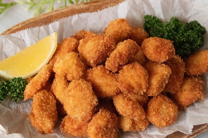 鶏ささみのポップコーンチキンが盛られた皿にレモンとパセリが添えられています。