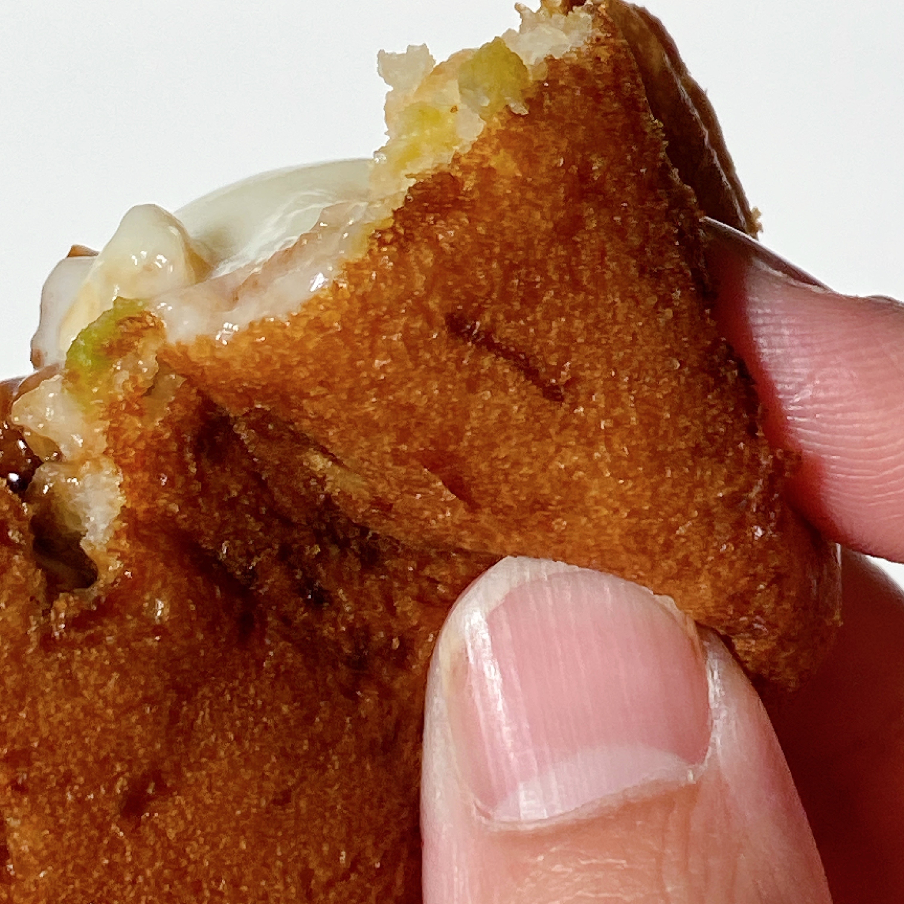 人が手で持って食べ物の一部をかじった様子。中に具材が見えている。