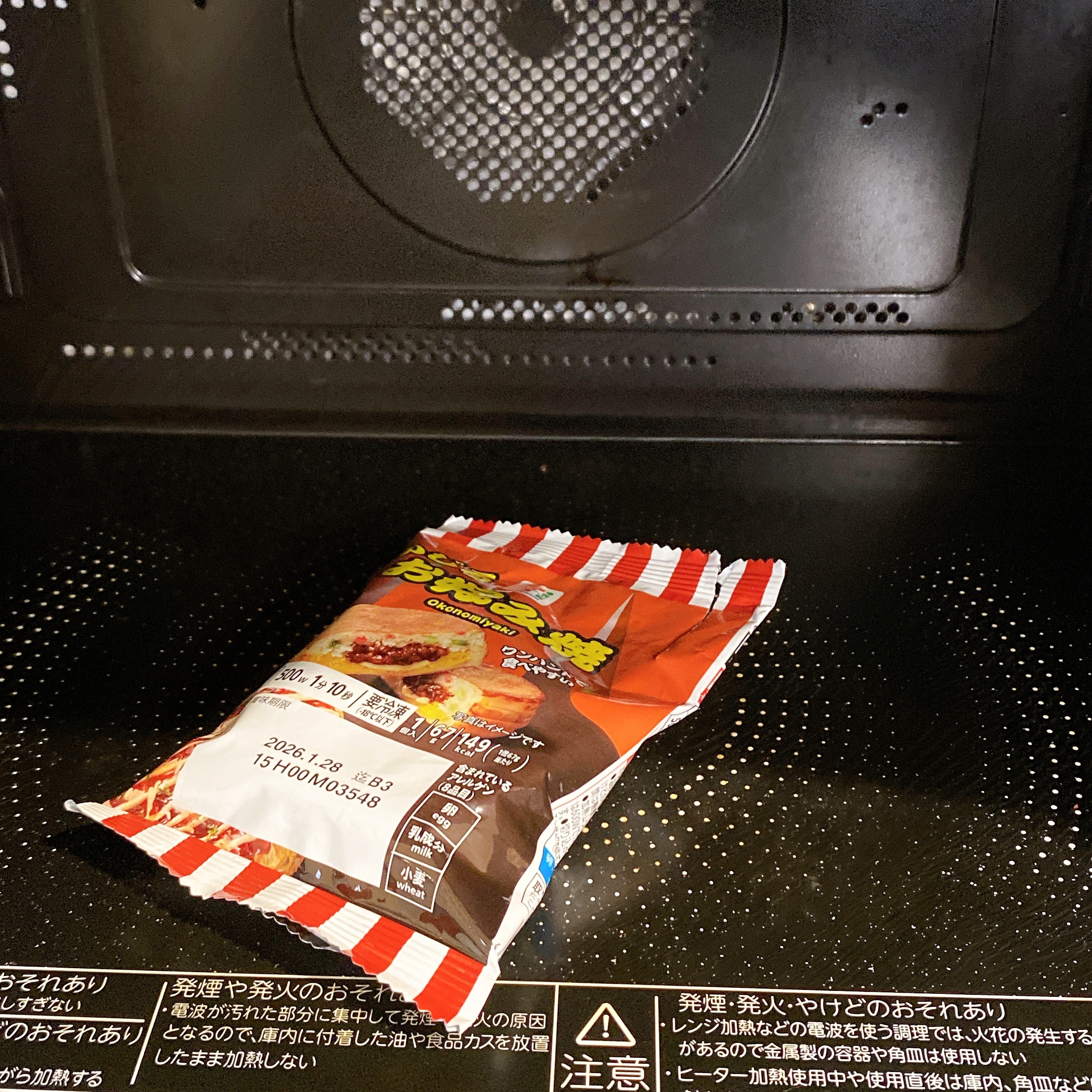 電子レンジの中にあるインスタント食品のパッケージ。温め準備が整った状態。