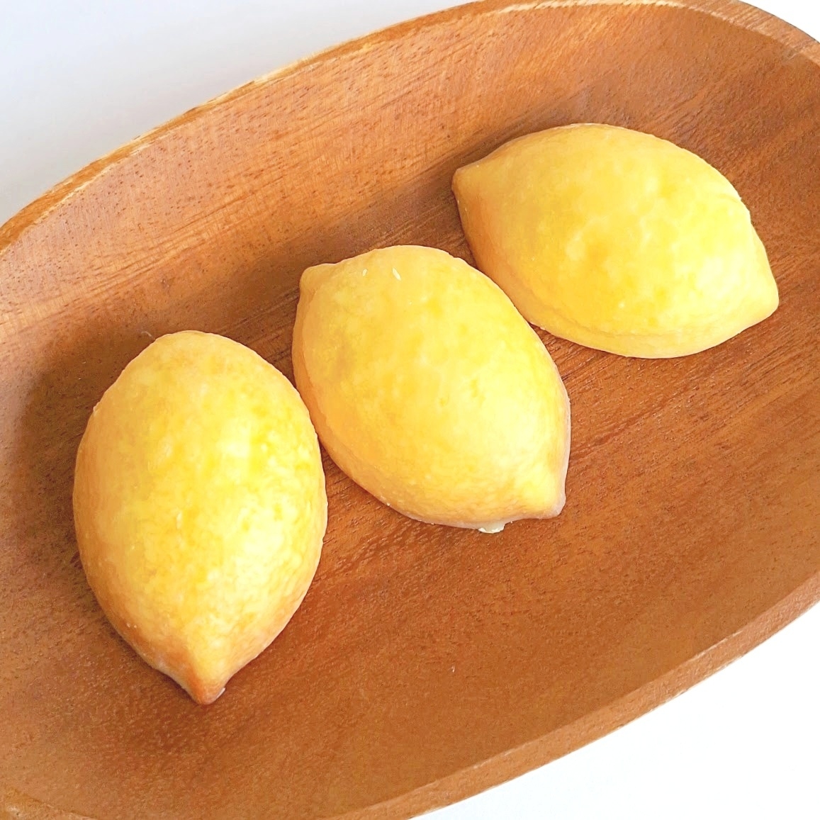 楕円形の木のトレイに、レモン形の焼き菓子が3つ並んでいます。