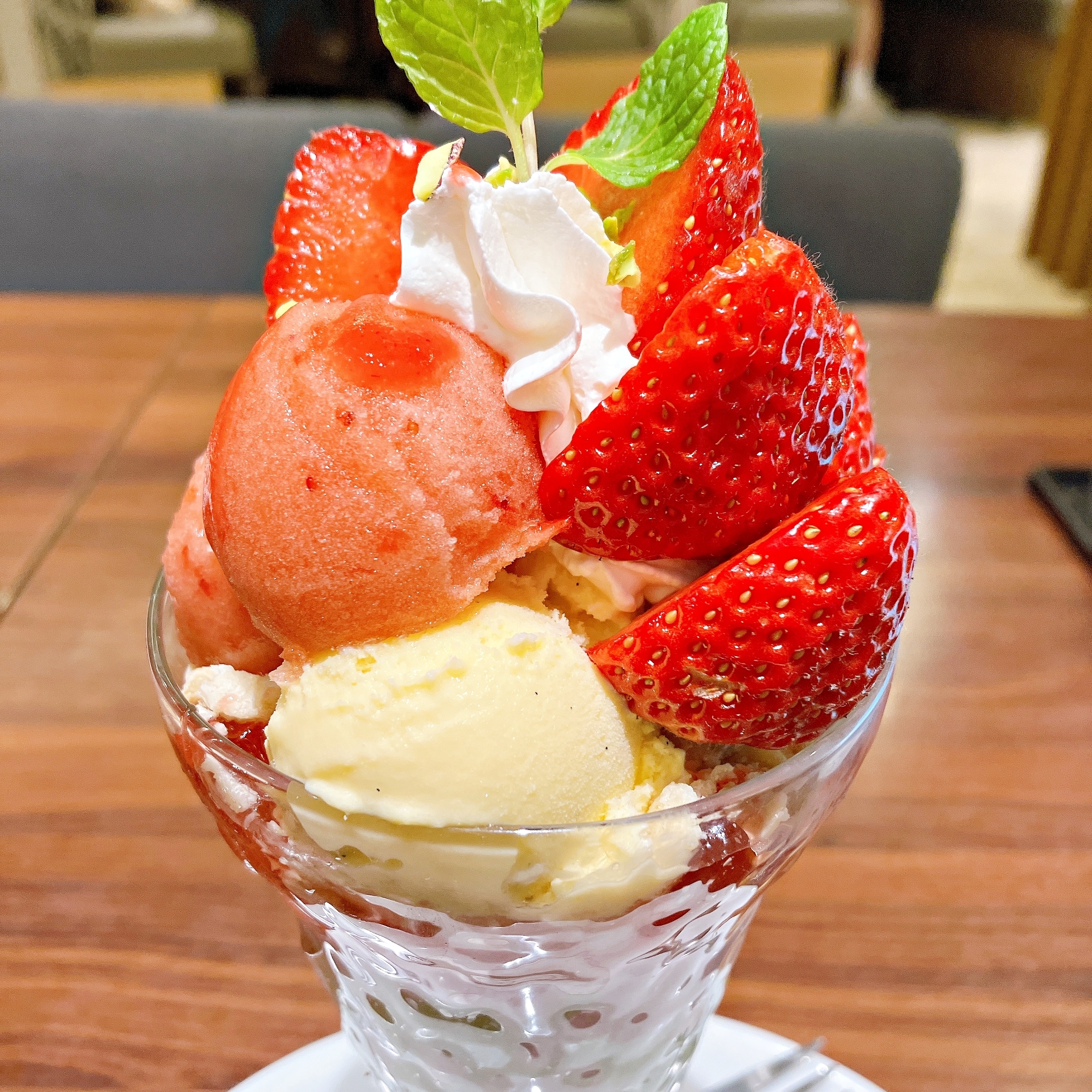 アイスクリームとイチゴが盛り付けられたパフェ、上にホイップクリームとミントの葉。