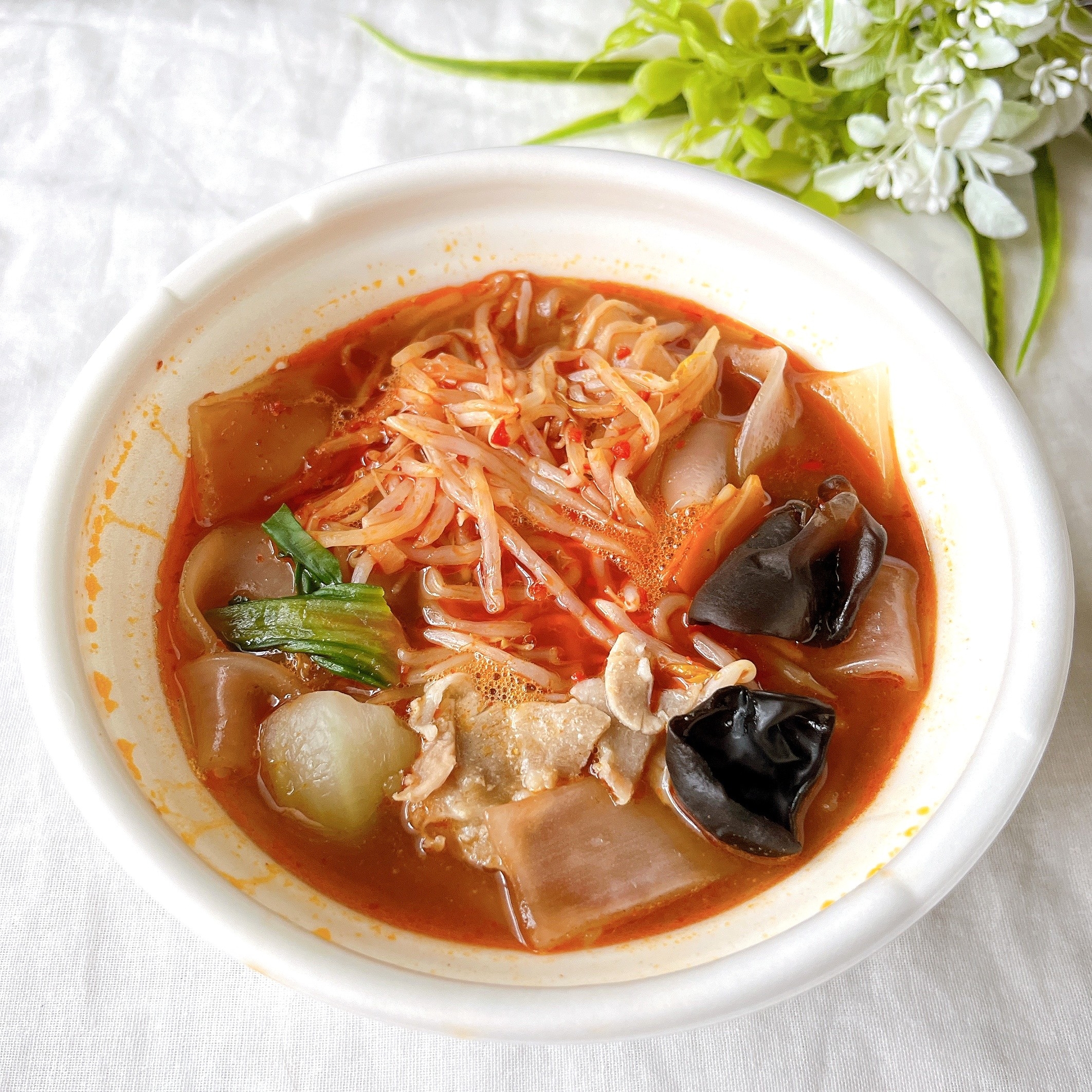 白いボウルに盛られたスープ麺、野菜ときのこがトッピングされています。
