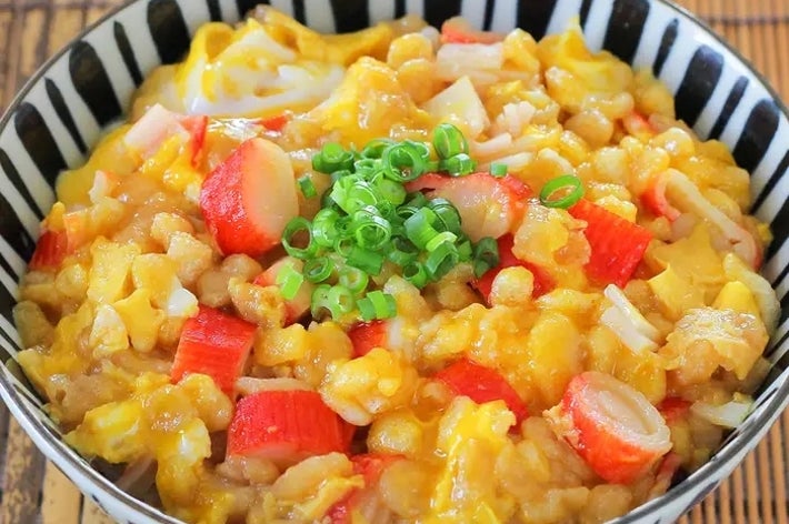 揚げ玉とネギをトッピングした丼、具材にカニカマと卵が混ざり、ボリューム感ある料理が特徴。