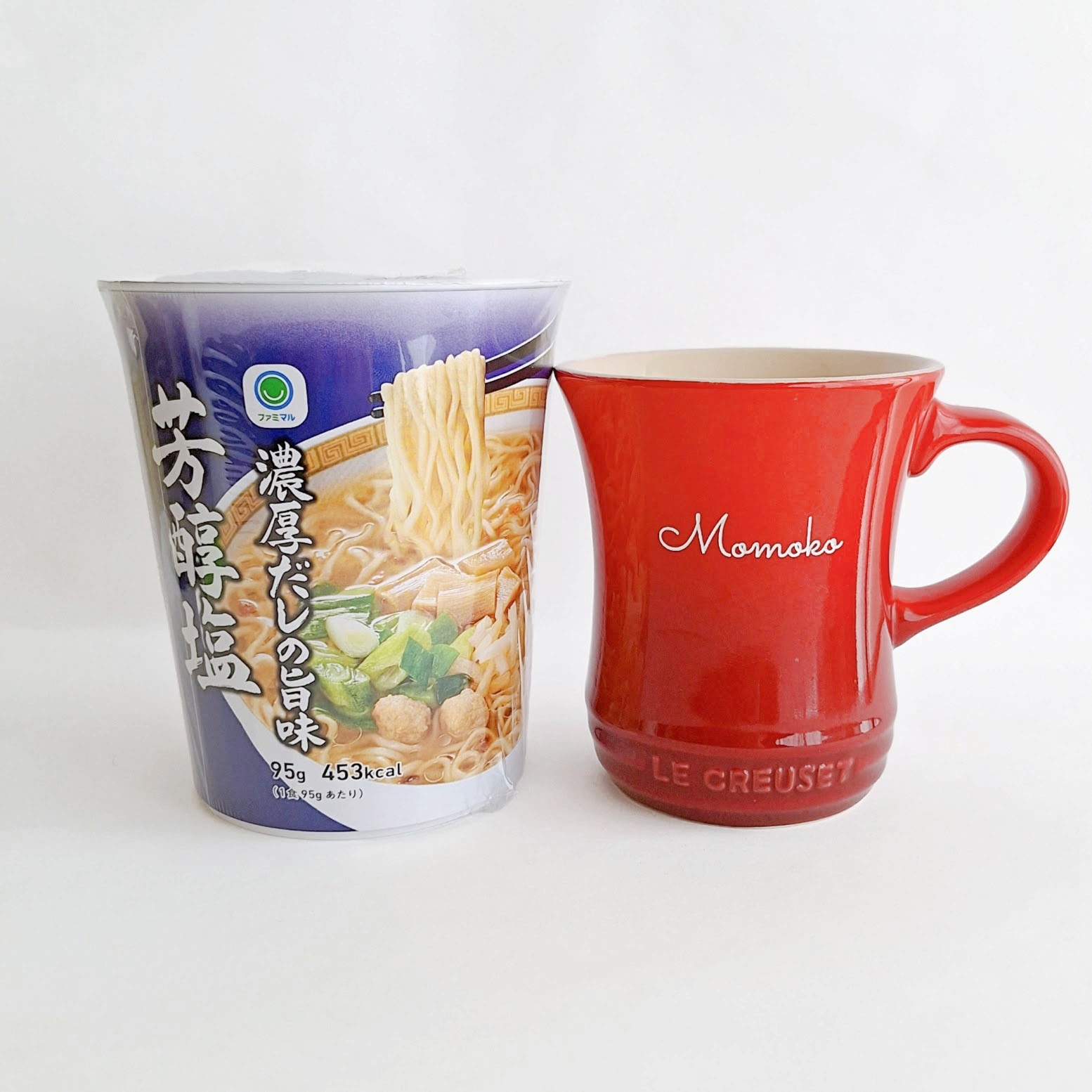 左にインスタントラーメンのカップ、右に赤いマグカップ。