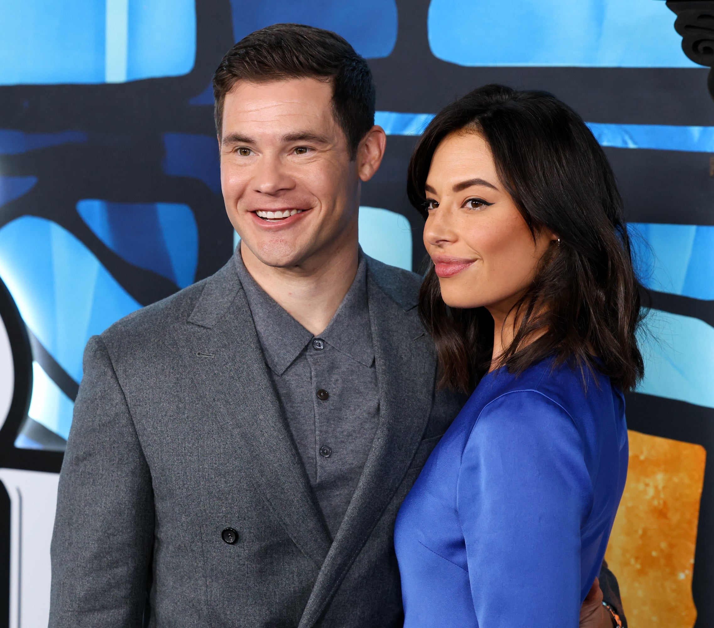 Adam Devine and Chloe Bridges posing together on a red carpet