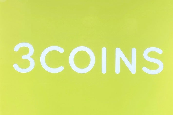 3COINSのロゴが中央に配置された看板。背景は立体的なデザインのパネル。