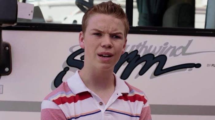 Person in a striped polo shirt standing outdoors, looking curious or confused. Background features a recreational vehicle