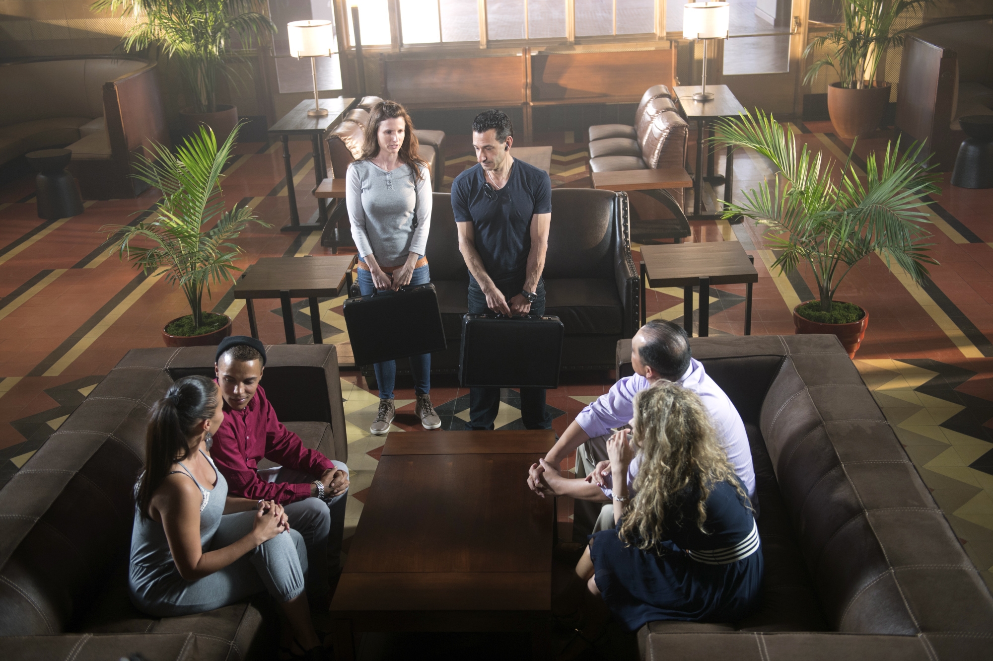 The Moyas and the Vendely-Salgados gather in a stylish room with leather couches and wooden tables, engaging in conversation
