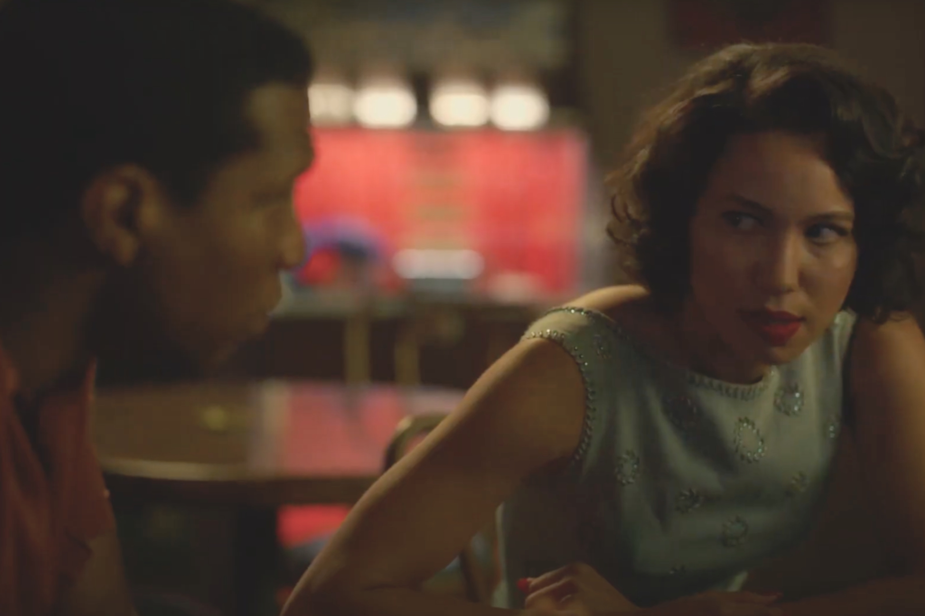 Characters from "Lovecraft Country" are sitting at a table in a dimly lit room, engaged in an intense conversation