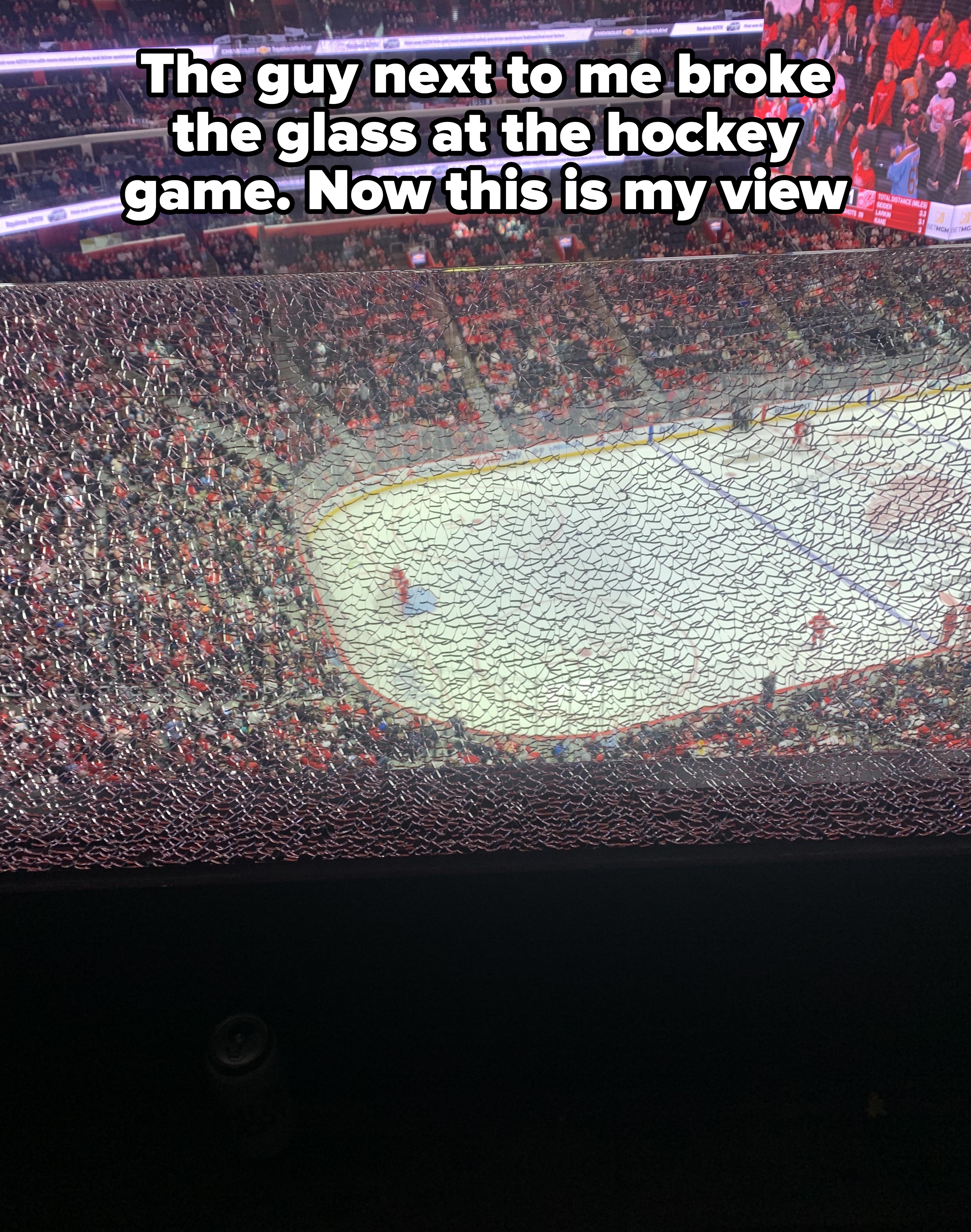 View of an ice hockey rink during a match with players on the ice and a large audience in the stadium
