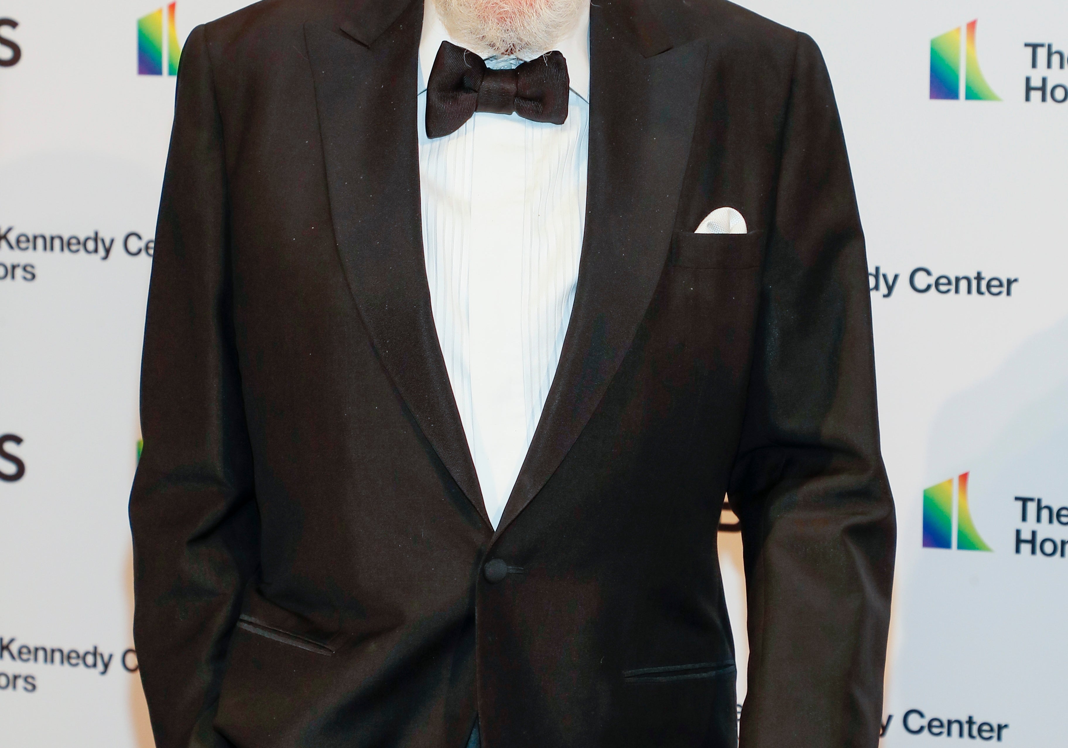 Person at the Kennedy Center Honors event, wearing a classic tuxedo with a bow tie, smiling and holding a cane