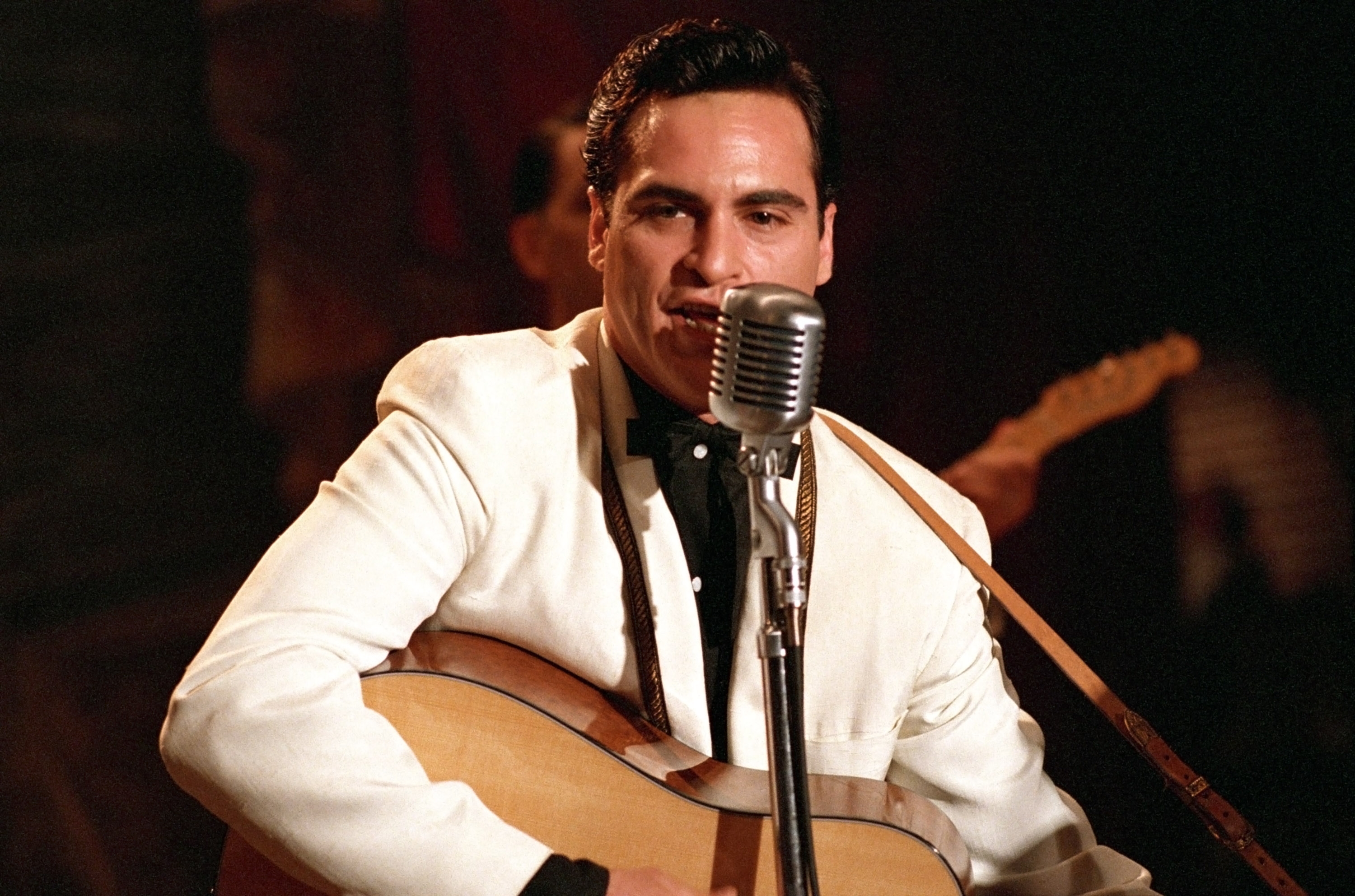Joaquin Phoenix as Johnny Cash in "Walk The Line" playing a guitar and singing into a microphone