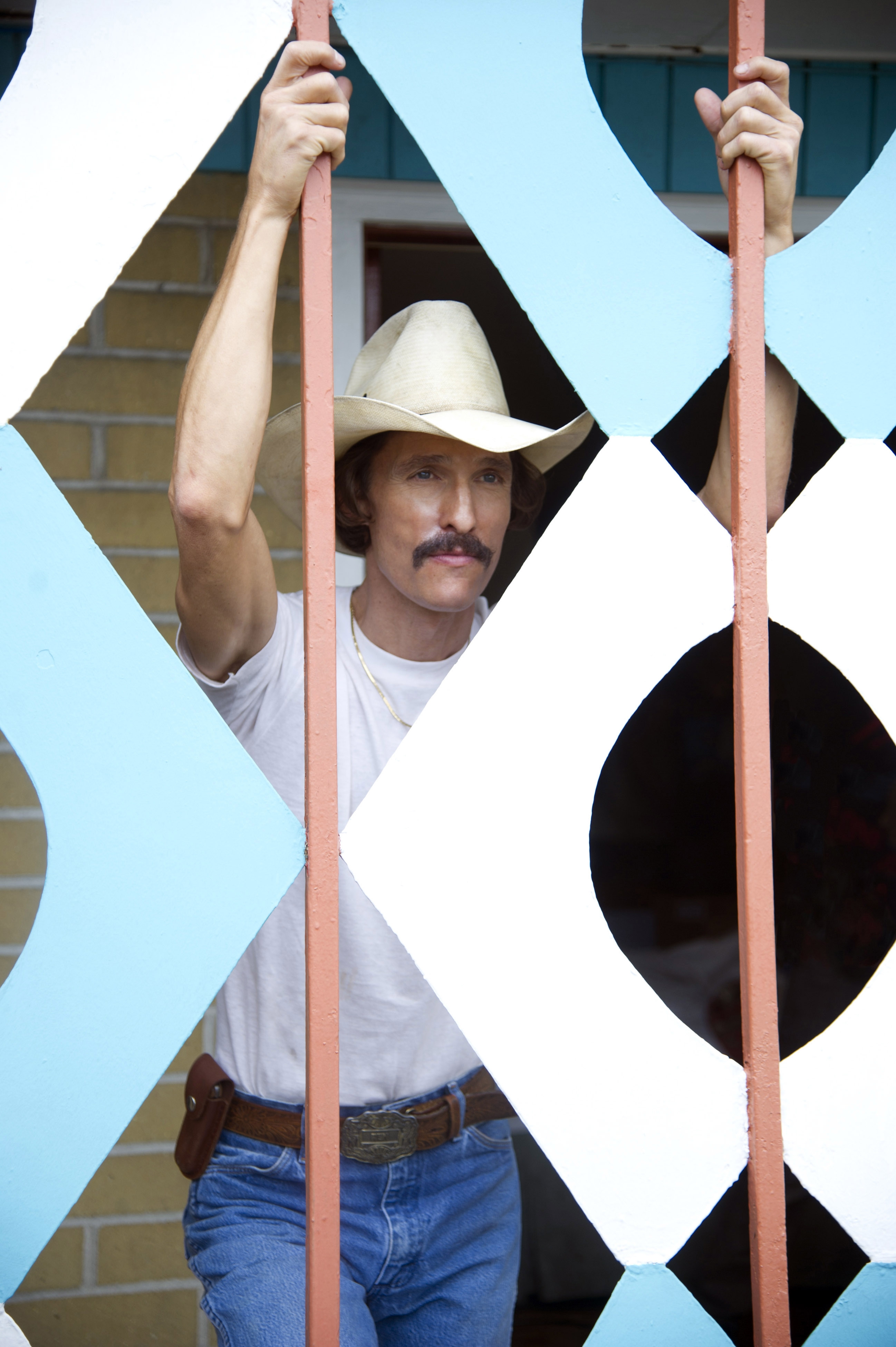 Matthew McConaughey as Ron Woodroof in "Dallas Buyers Club" looking through a grate in a cowboy hat