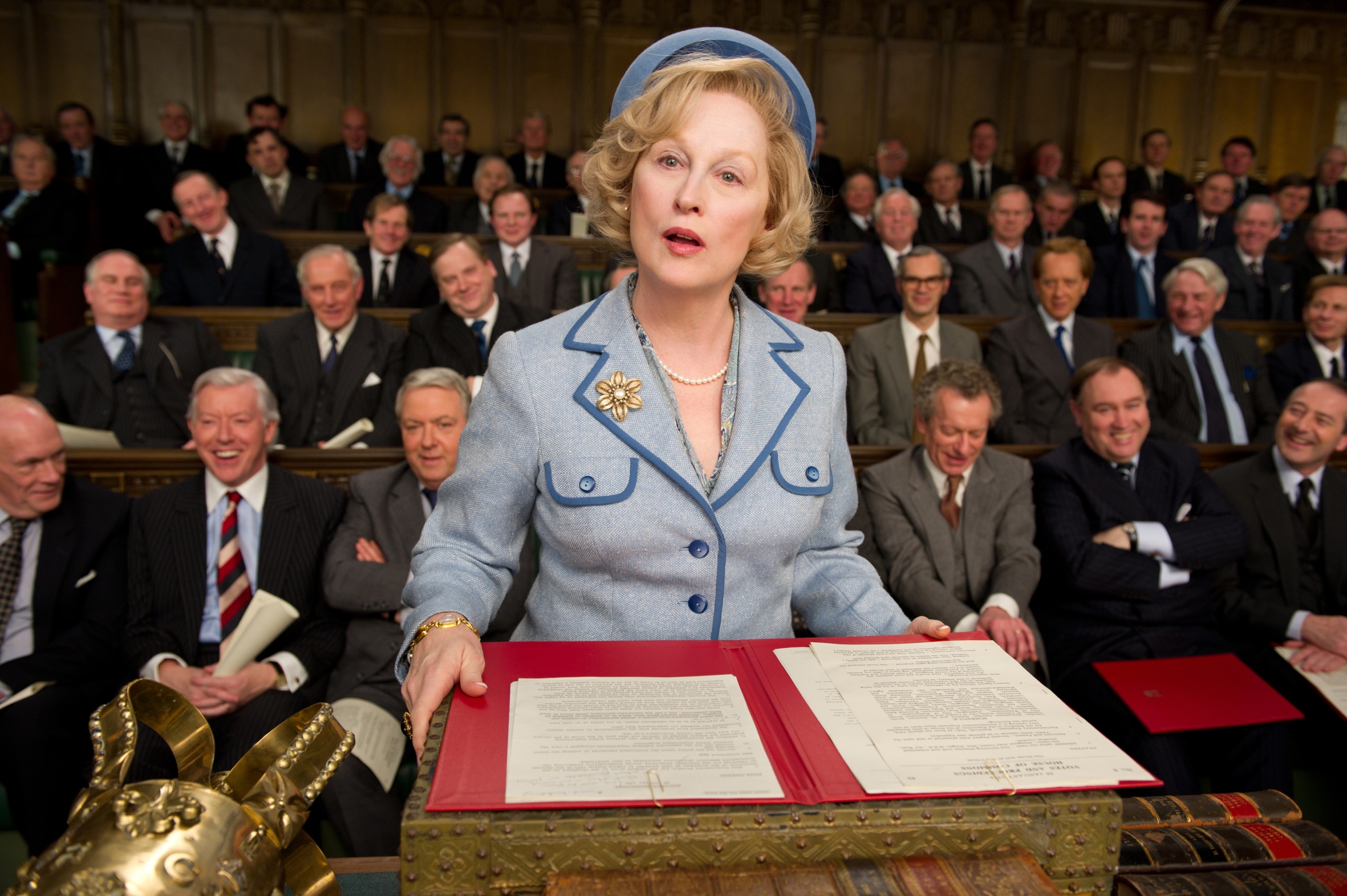 Meryl Streep as Margaret Thatcher in "The Iron Lady" in Parliament with politicians behind her as she reads a bill