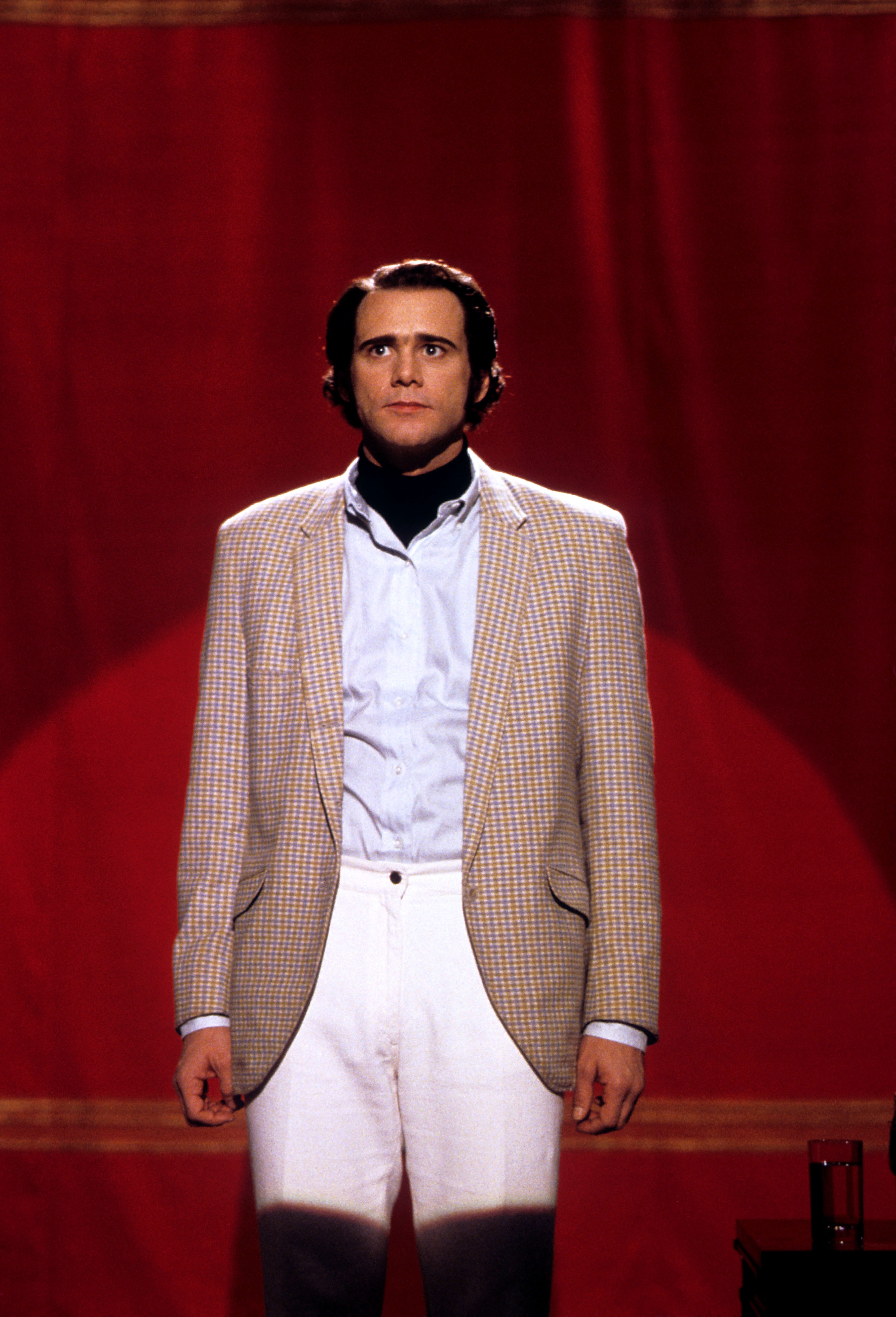 Jim Carrey as Andy Kaufman in "Man on the Moon" standing in front of a curtain