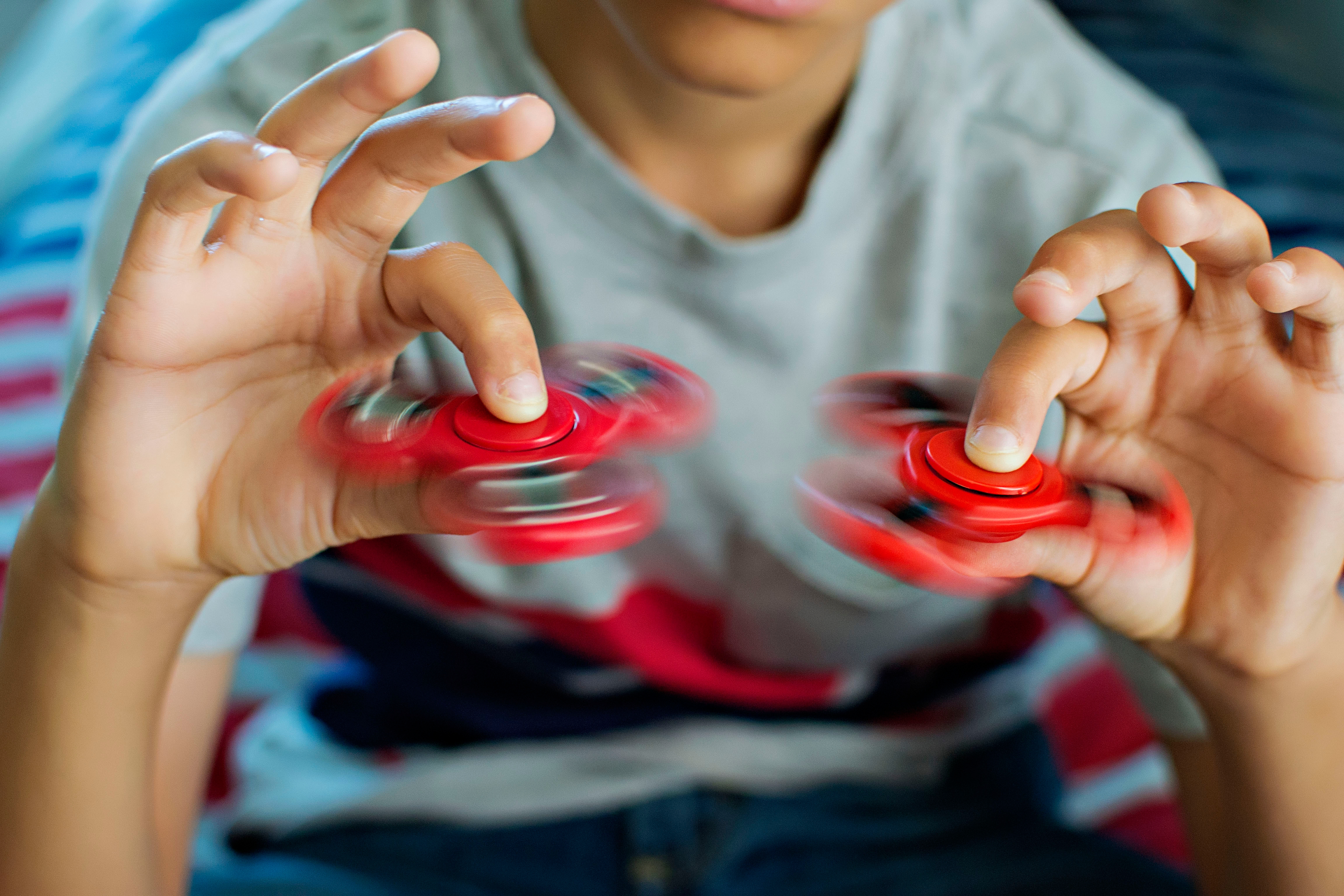 Person spinning two fidget spinners rapidly with hands, focus on motion