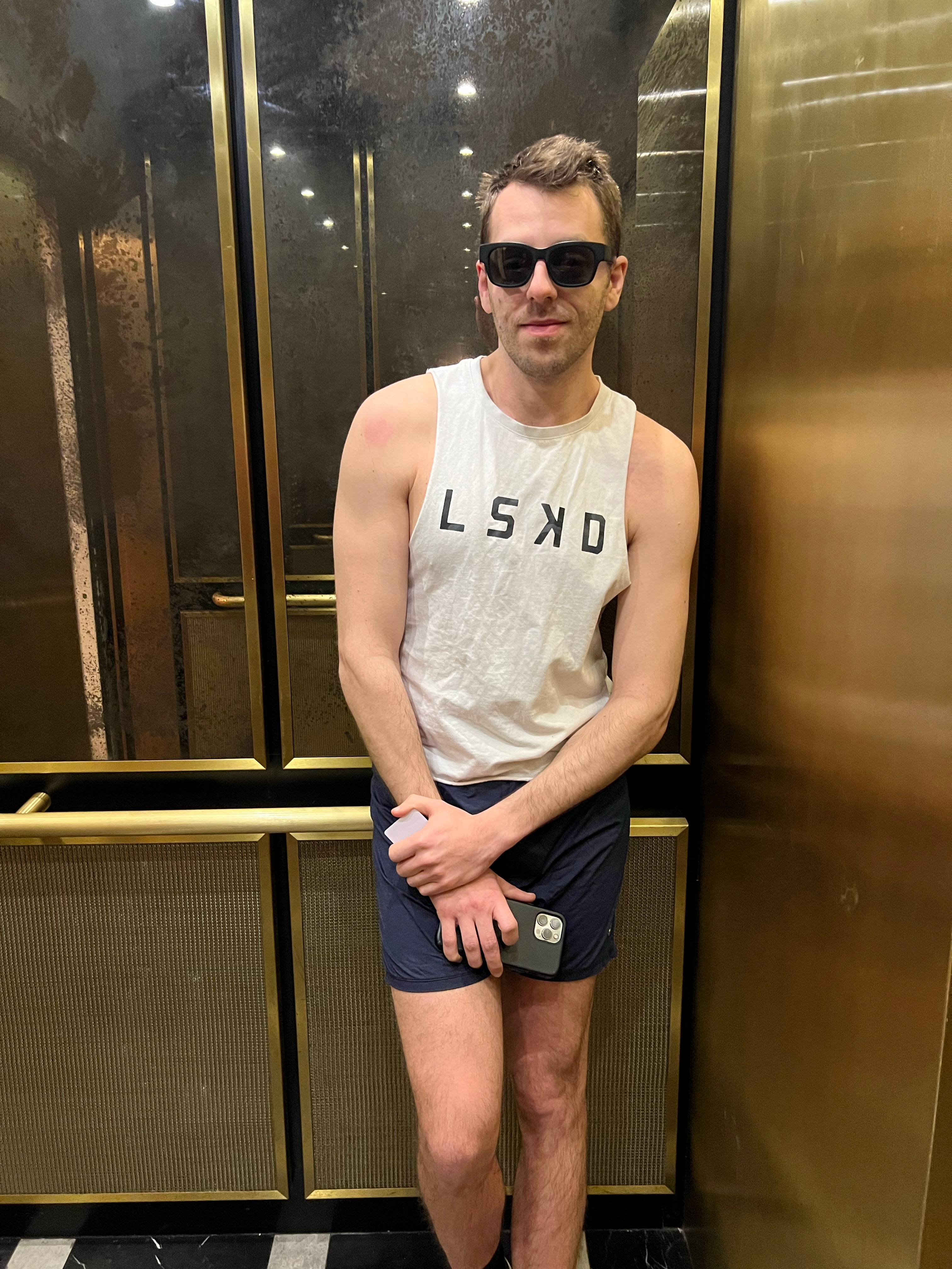 Me standing in an elevator with sunglasses on while wearing gym clothes