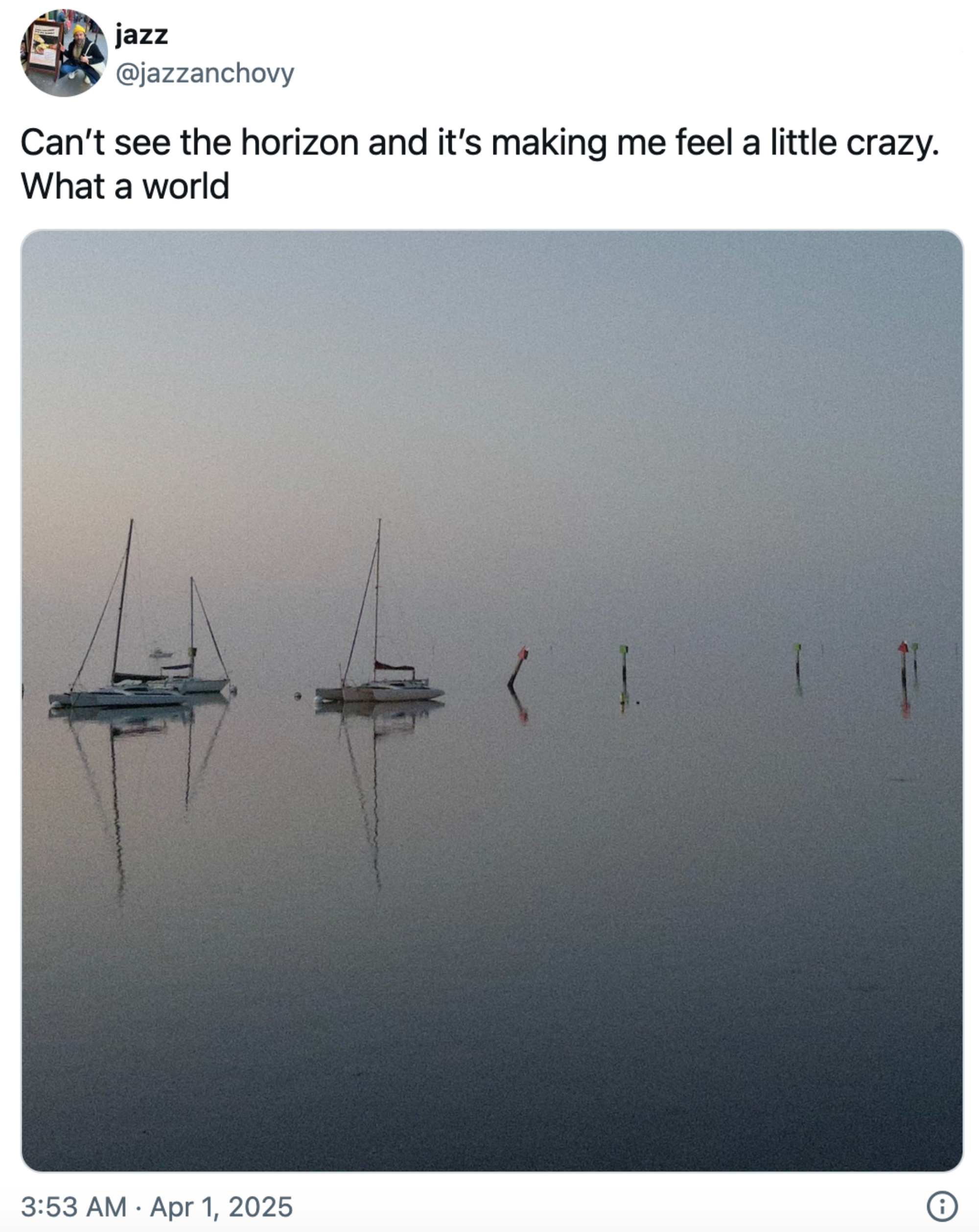 Båter på rolig vann under en tåkete himmel; Bildetekst reflekterer over begrenset horisont synlighet, og fremkaller surrealistiske følelser om verden