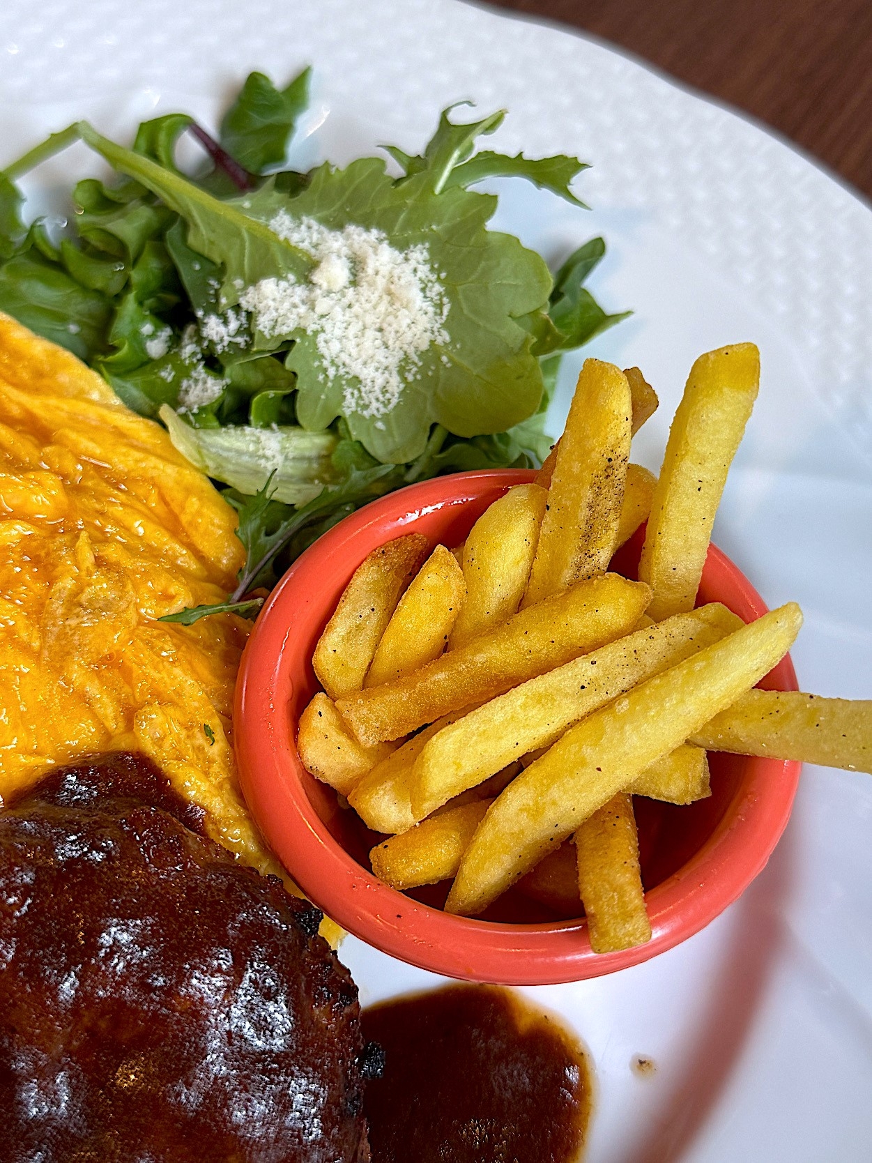 Plate with fries, scrambled eggs, a small salad, and a portion of meat with sauce