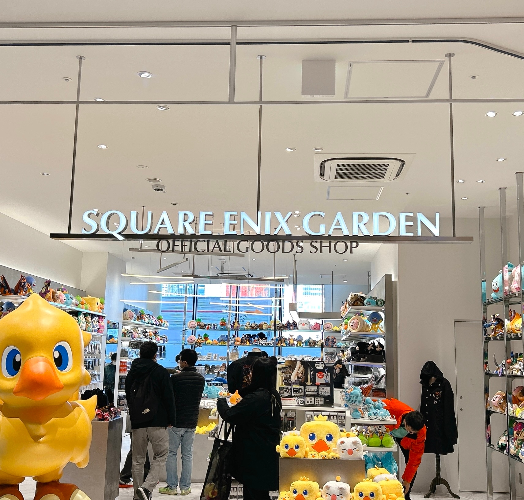 スクウェア・エニックスショップの入り口に並ぶおもちゃやグッズ、店内の客は何かを選んでいる様子。