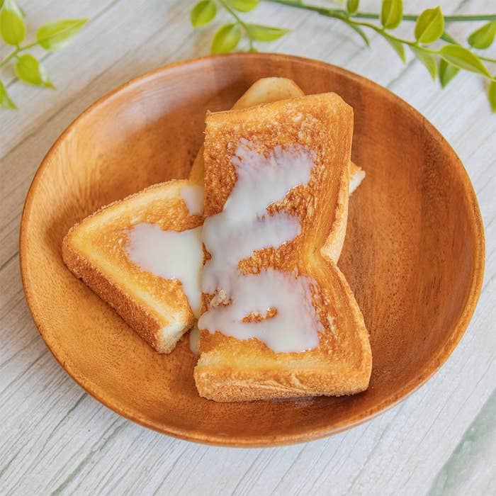 木のお皿に盛られたトーストの上に練乳がかかった様子。