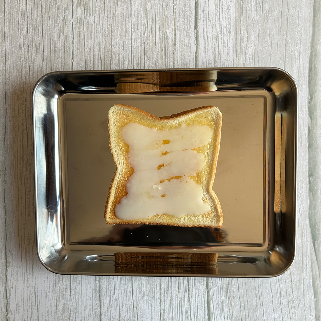 食パンの上に練乳が塗られたトーストが金属製のトレイに置かれています。