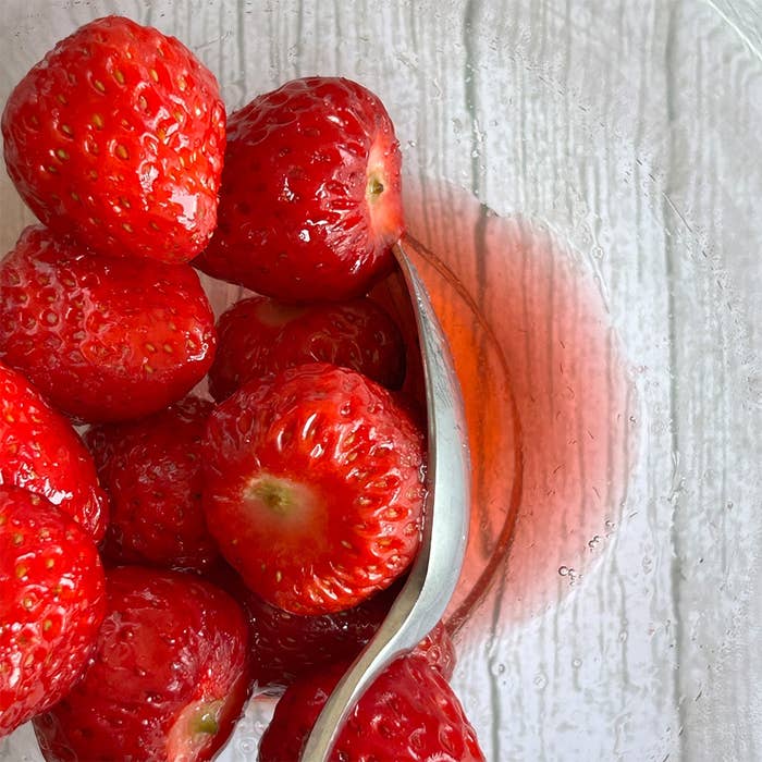 ガラスボウルに入った新鮮なイチゴとスプーン。