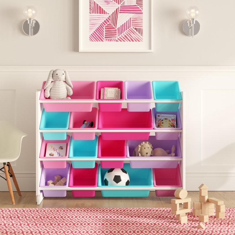 Storage organizer with colorful bins holding a stuffed rabbit, a soccer ball, books, and toys, under geometric wall art
