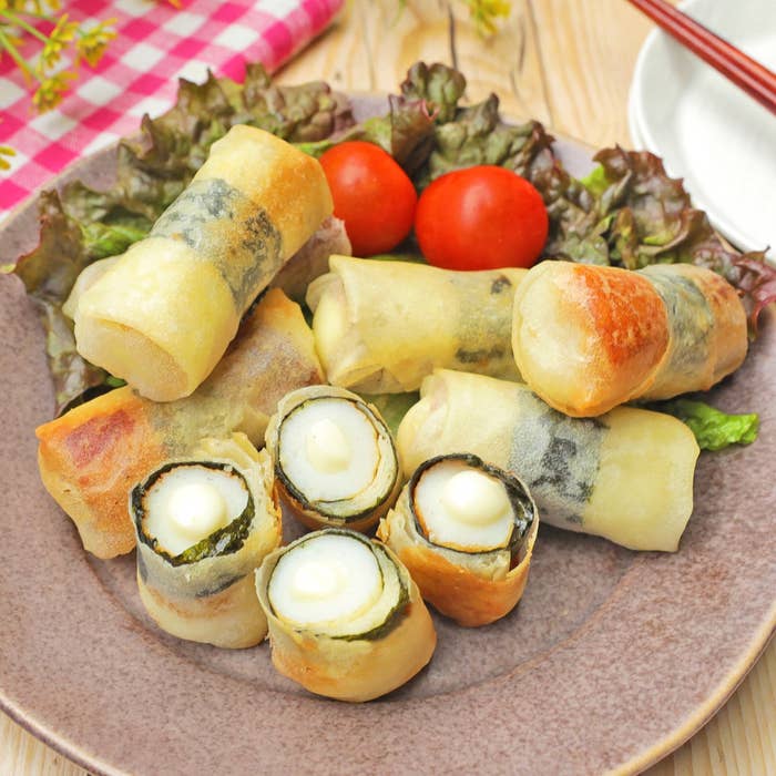 お皿に盛られた揚げた春巻きとミニトマト。春巻きの中には、海苔で巻かれたゆで卵が見える。