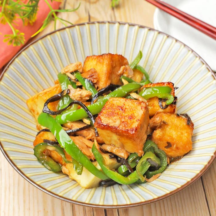 豆腐とピーマンの炒め物が皿に盛られている。野菜と豆腐が混ざり、食欲をそそる一品。