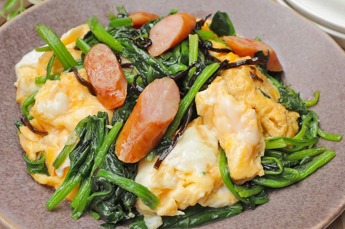 ソーセージと卵、ほうれん草の炒め物が盛られた皿。質感の異なる素材が食欲をそそる。