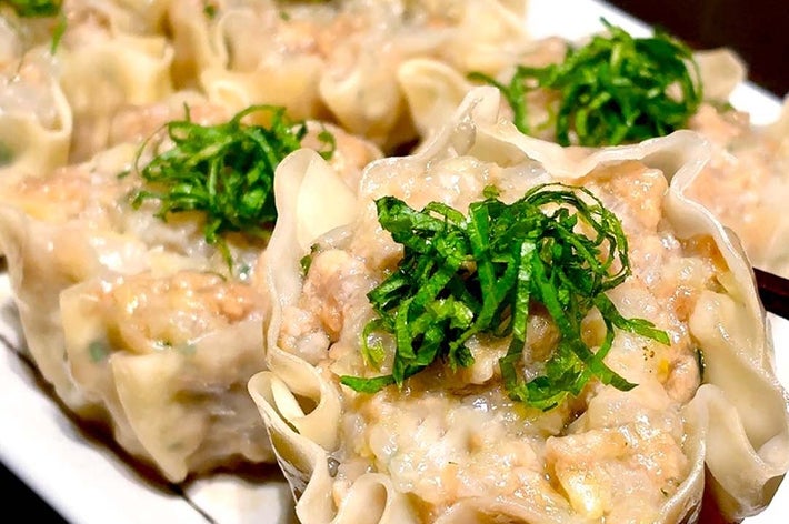 皿に盛られた焼売。一つ一つに刻んだ緑の野菜がトッピングされています。