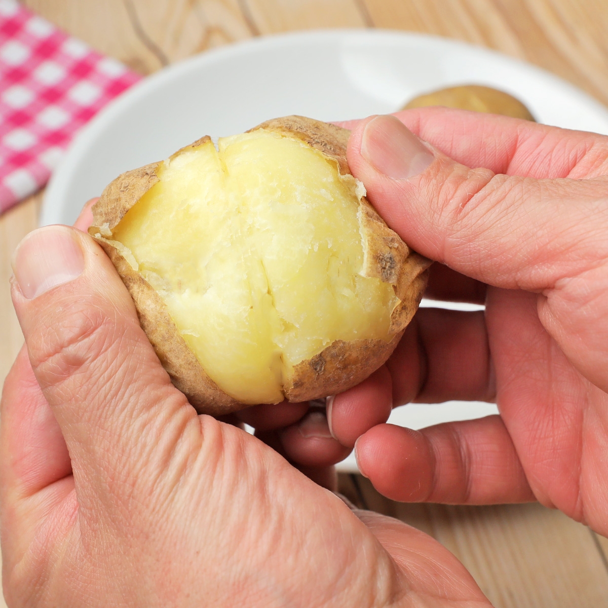じゃがいもを手で割った瞬間の様子。皿の上で、じゃがいもの内側が見えています。