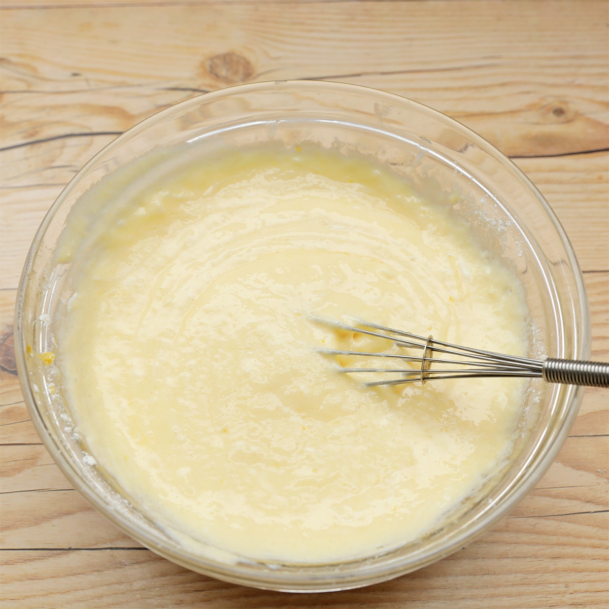 ボウルに入ったクリーム状の生地を泡立て器で混ぜている様子。
