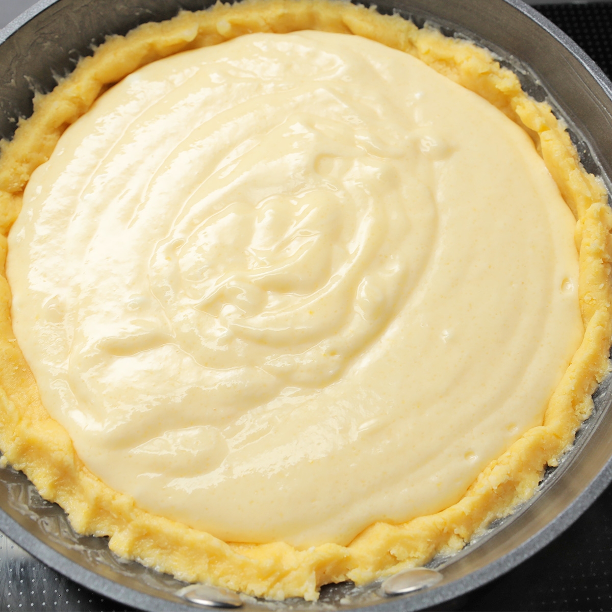 パイ生地にクリームまたは生地のようなフィリングを流し込んで準備中のパイ。