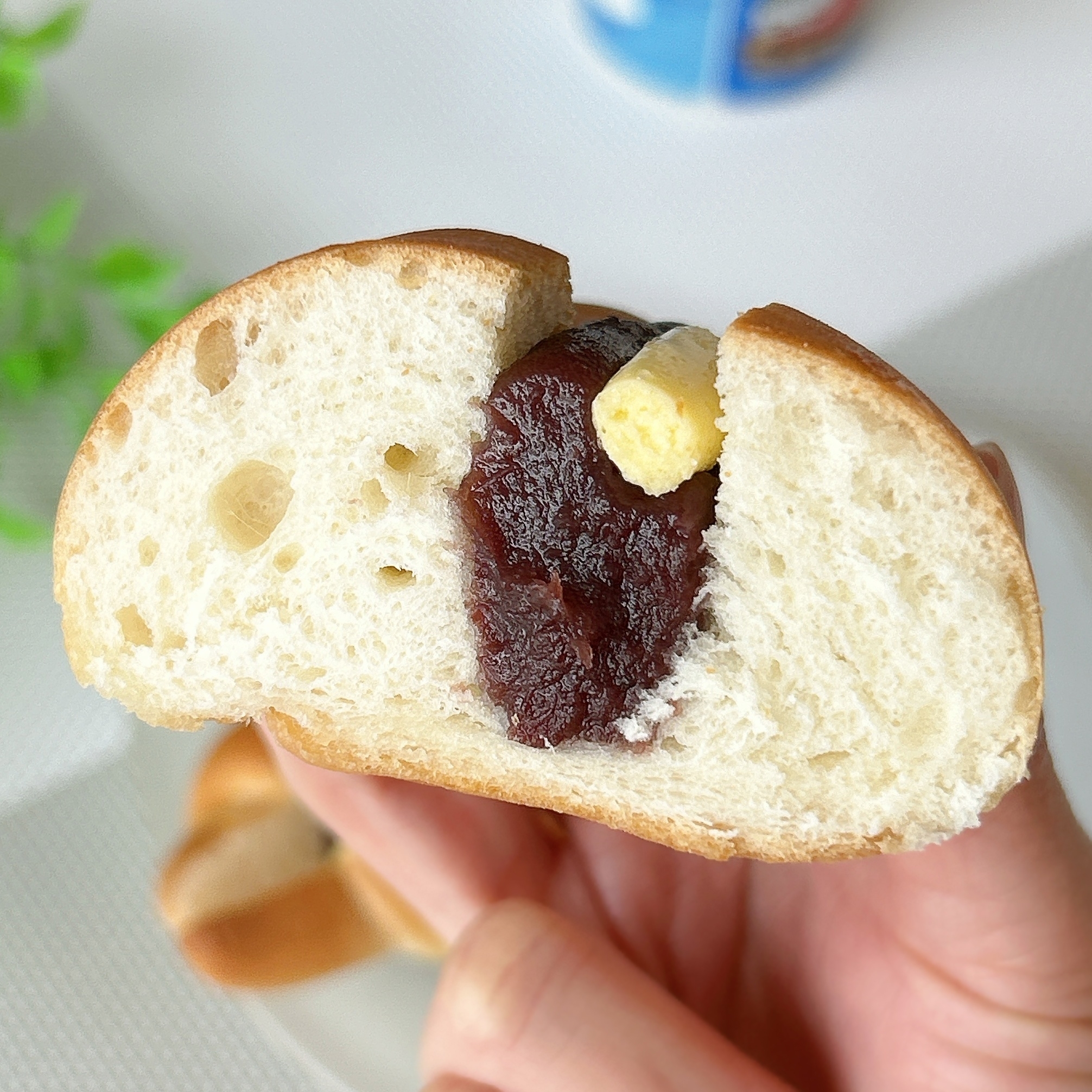 手に持たれたパンの断面。中にあんことバターがたっぷり詰まっている。