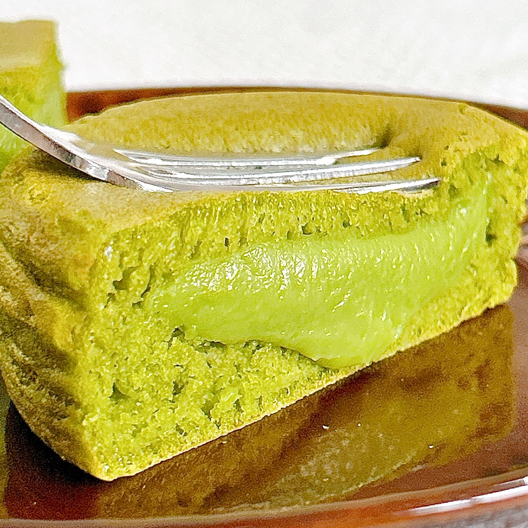 フォークが刺さった抹茶フレーバーのケーキが皿に乗っている。