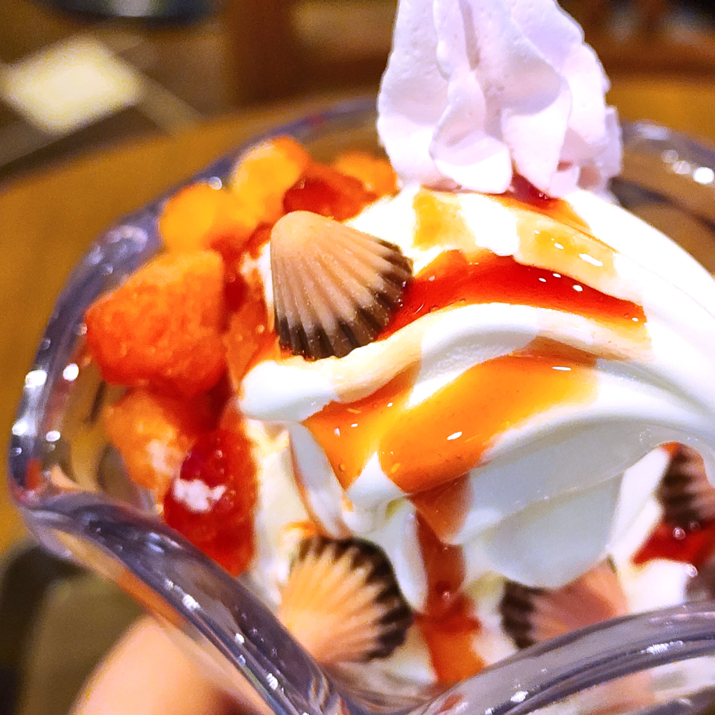 アイスクリームパフェに苺ソース、クリーム、チョコレートチップがトッピングされ、美味しそうなデザートが強調されています。