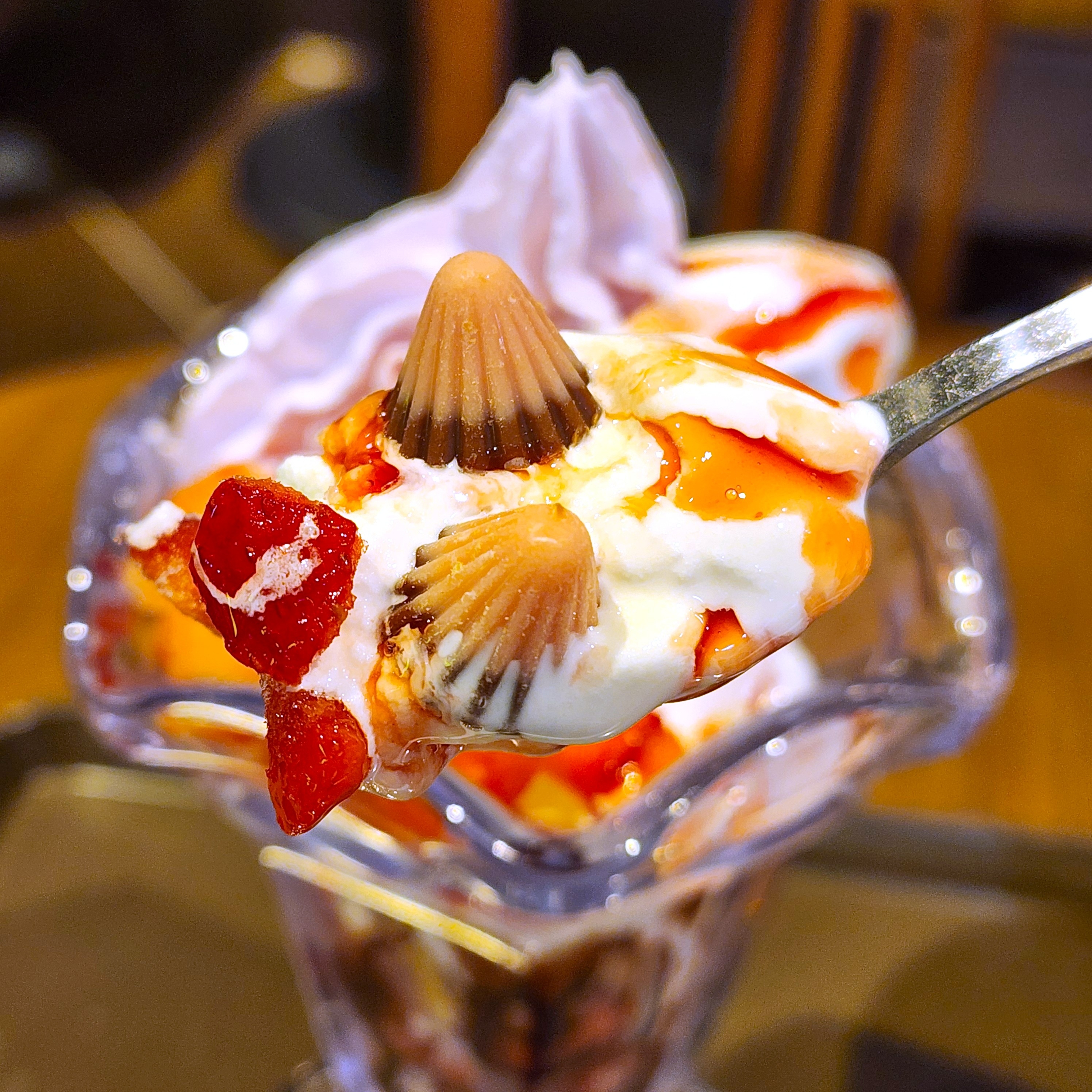 デザートパフェのアップ。イチゴ、クリーム、チョコレートがトッピングされ、美味しそうに盛り付けられている。