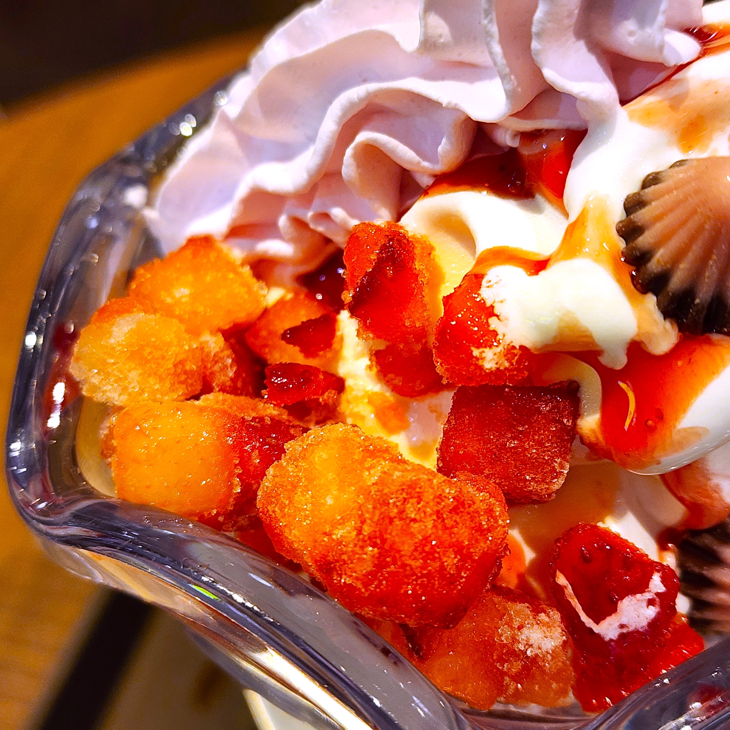 パフェの上に新鮮なフルーツが載ったクリームデザートのクローズアップ。リアルな食感と美味しさが強調されています。