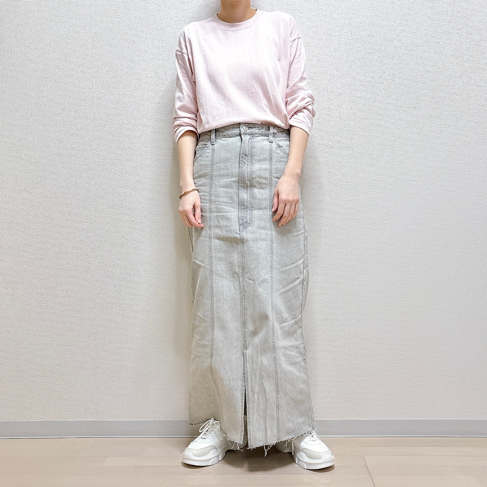 人物がファッション、シンプルな長袖シャツとデザイン性のある長いスカート、スニーカーを着用しています。