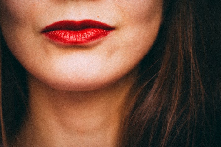 女性の顔の一部。口元が映り、光沢のある口紅をつけている。