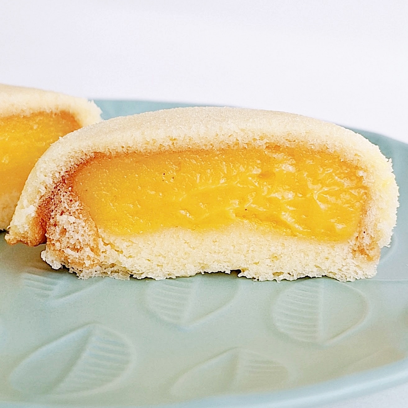 半分にカットされたマンゴー風味のムーンケーキが青い皿にのっている。