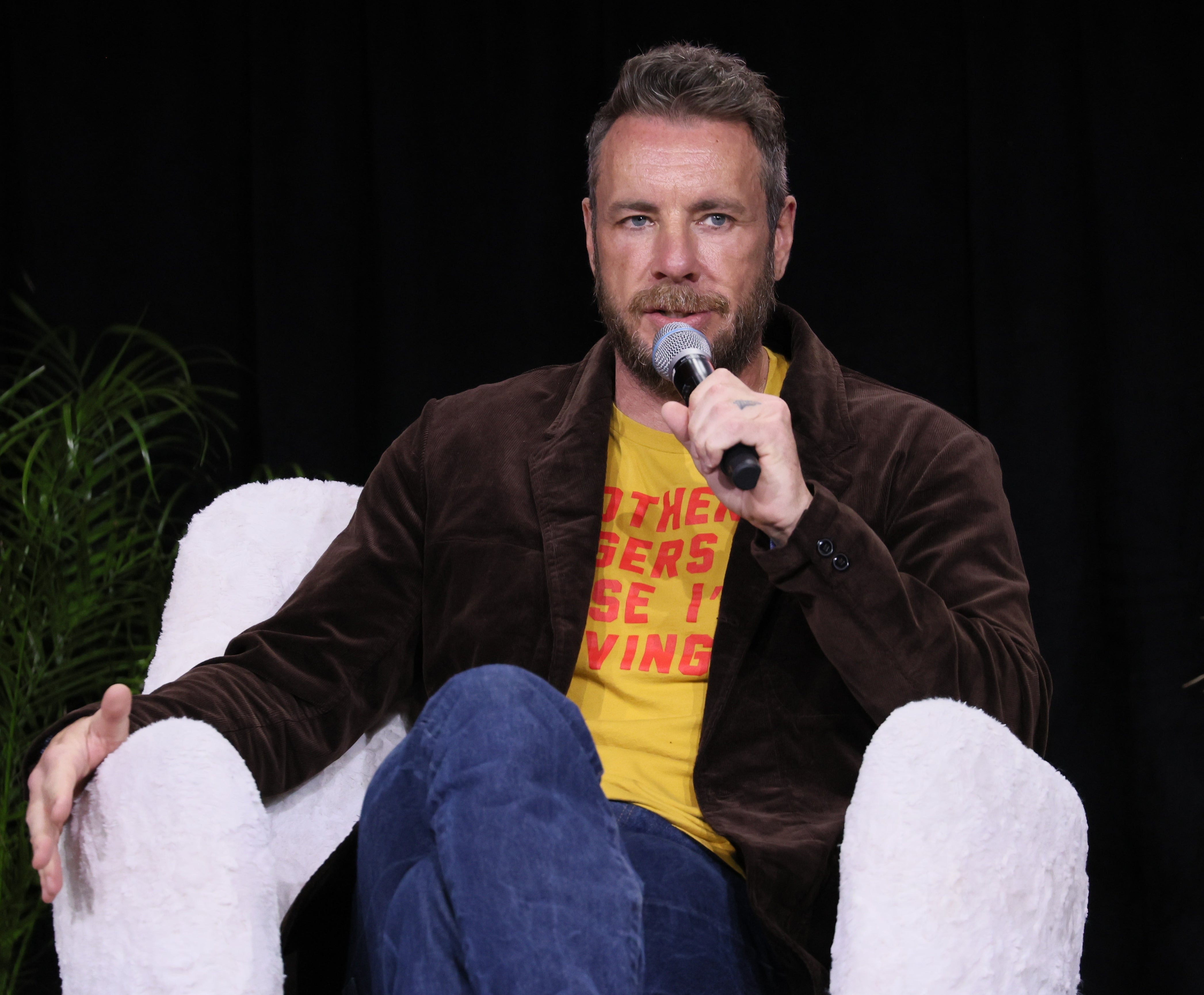 Dax Shepard seated on stage with microphone
