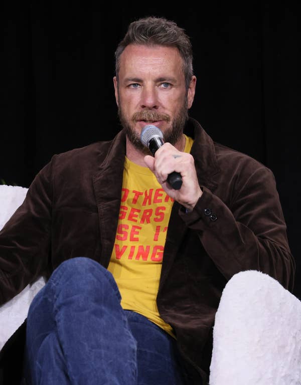 Dax Shepard seated on stage with microphone