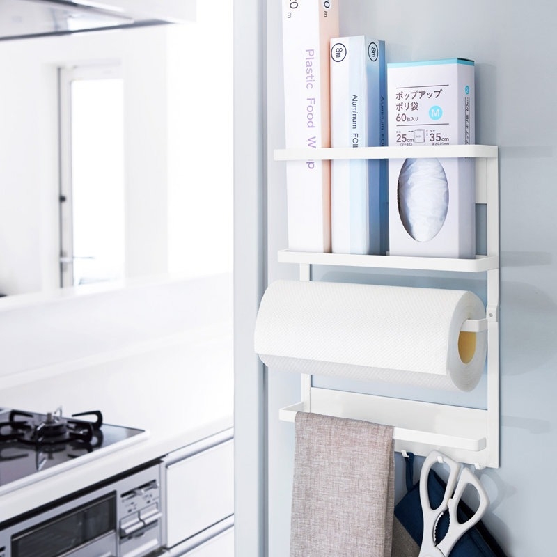 Kitchen storage organizer mounted on a wall, holding foil, paper towels, and kitchen wraps, designed for efficient use of space