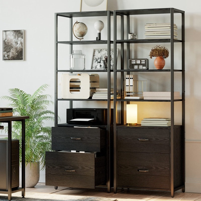 Modern black shelving unit with drawers, books, decor items, potted plant, and a framed picture in a stylish home office setting