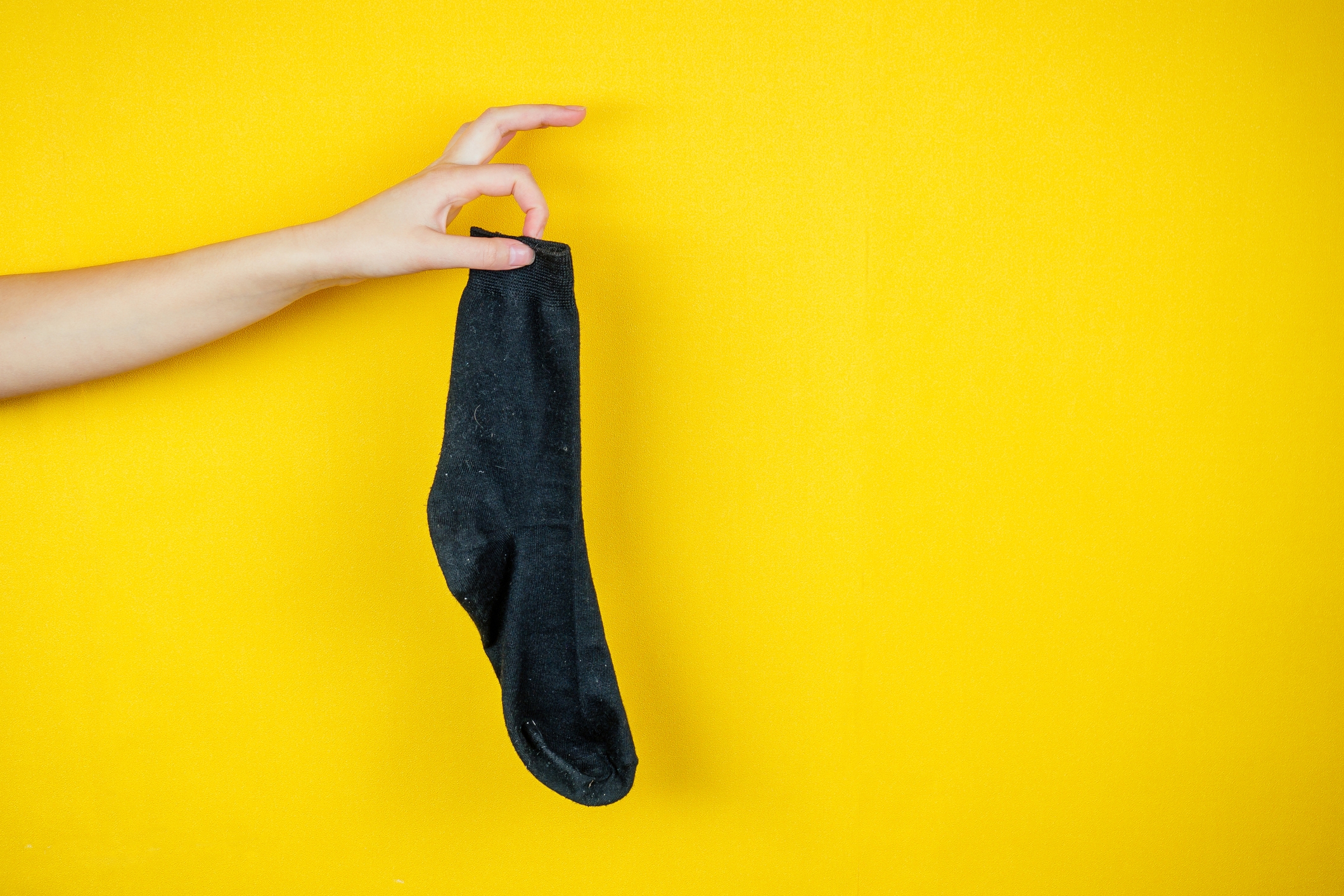 A hand holds up a single sock against a yellow background, suggesting a quirky or humorous internet find